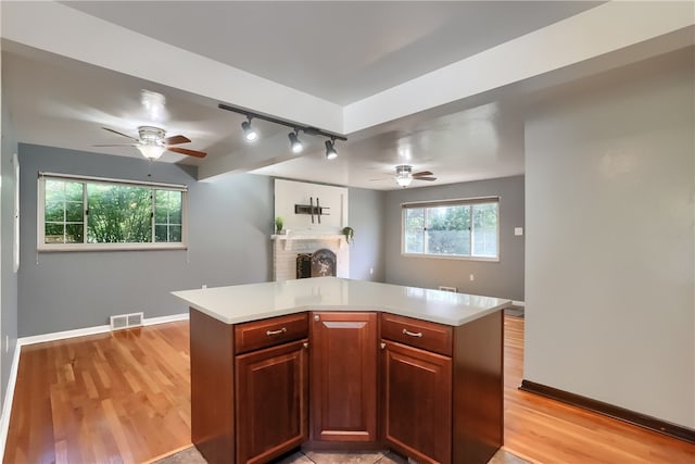 kitchen with a brick fireplace, ceiling fan, light hardwood / wood-style floors, and track lighting