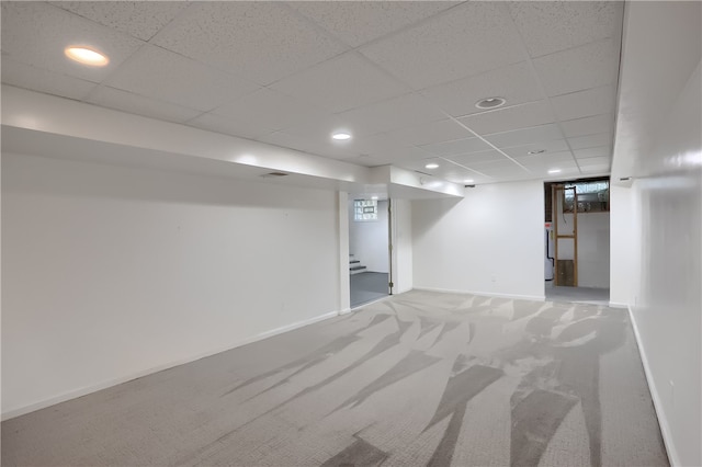 basement featuring a paneled ceiling and carpet floors