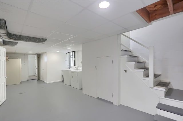 basement with washing machine and dryer, white refrigerator, and a paneled ceiling