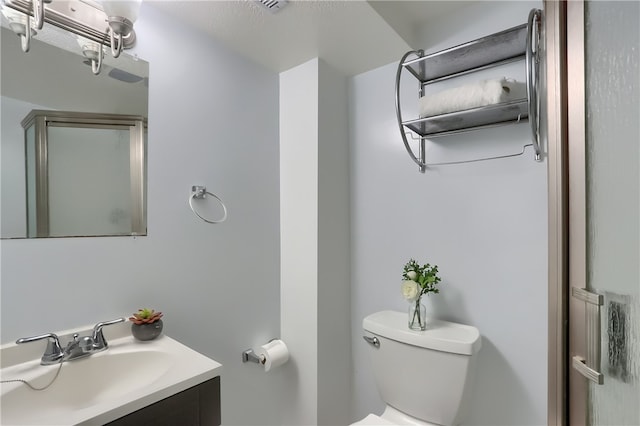 bathroom with a shower with door, vanity, and toilet