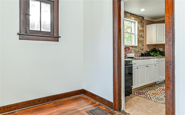 corridor featuring crown molding, sink, and light tile patterned floors