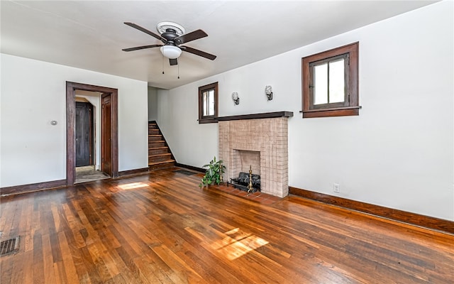 unfurnished living room with ceiling fan, a fireplace, and dark wood-type flooring