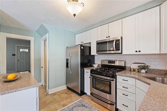 kitchen featuring a textured ceiling, tasteful backsplash, sink, white cabinetry, and appliances with stainless steel finishes