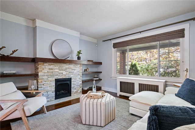 living room with wood-type flooring, a fireplace, crown molding, and radiator heating unit