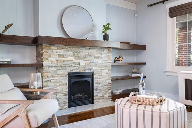 living room featuring a stone fireplace, wood walls, and hardwood / wood-style floors