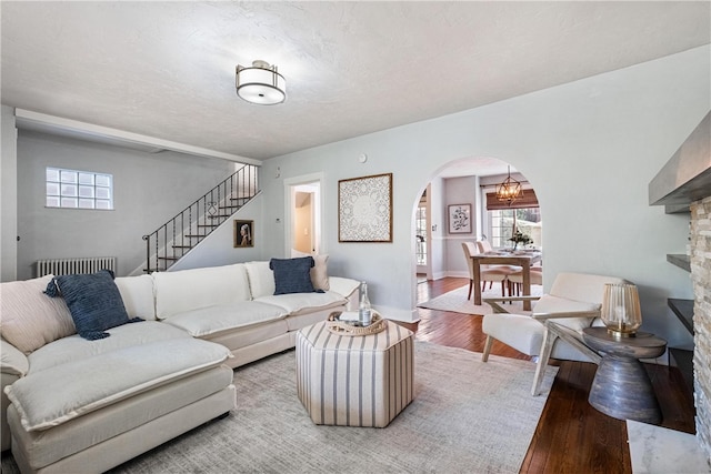 living room featuring wood-type flooring, a textured ceiling, and a notable chandelier