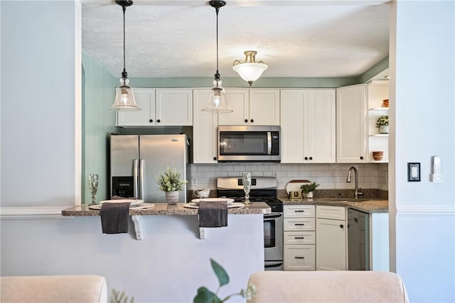 kitchen featuring white cabinets, appliances with stainless steel finishes, sink, and decorative light fixtures