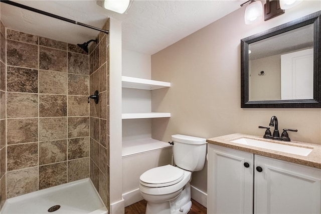 bathroom featuring vanity, toilet, hardwood / wood-style flooring, and tiled shower