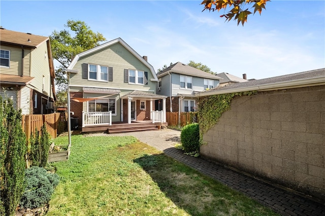 back of property with a yard and a wooden deck