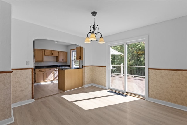 kitchen with an inviting chandelier, decorative light fixtures, light hardwood / wood-style floors, and kitchen peninsula