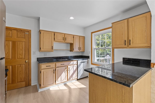 kitchen with light hardwood / wood-style flooring, dark stone countertops, kitchen peninsula, and stainless steel dishwasher