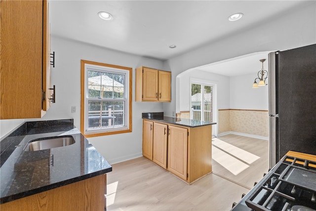 kitchen featuring pendant lighting, stainless steel fridge, kitchen peninsula, and plenty of natural light