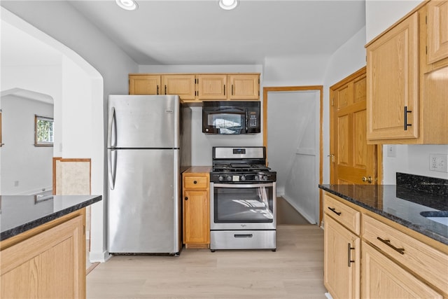 kitchen featuring dark stone countertops, light brown cabinetry, light hardwood / wood-style flooring, and stainless steel appliances