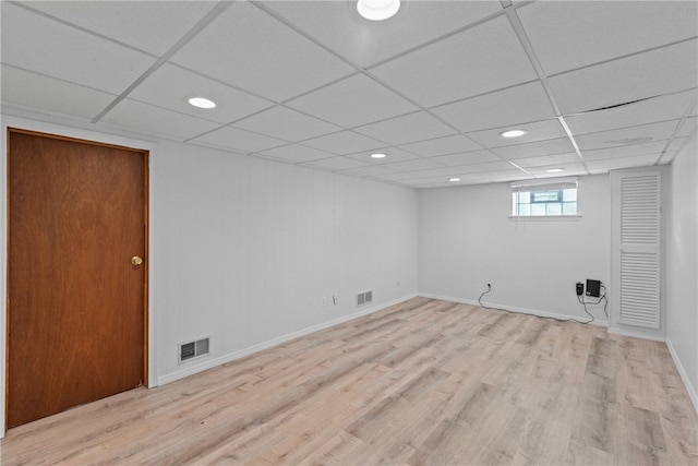 basement featuring light wood-type flooring and a drop ceiling