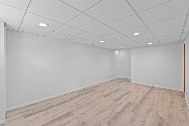 basement featuring a paneled ceiling and light hardwood / wood-style flooring