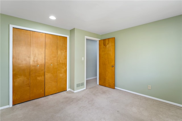 unfurnished bedroom with light carpet and a closet