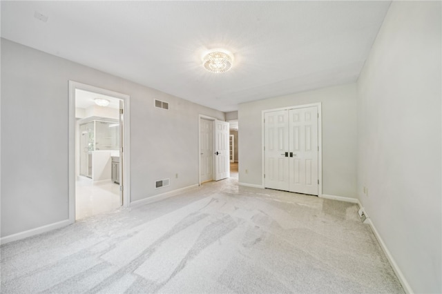 interior space featuring light carpet, ensuite bath, and a closet