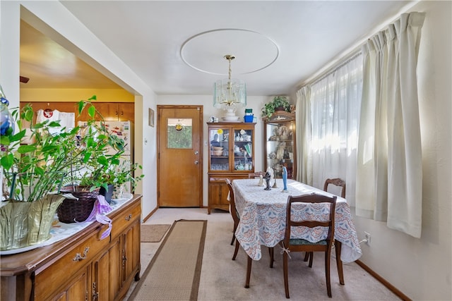 carpeted dining area with a chandelier