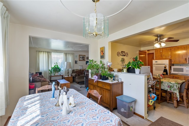 dining area featuring light colored carpet and ceiling fan with notable chandelier