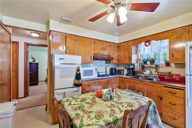 kitchen with white appliances, sink, light carpet, and ceiling fan