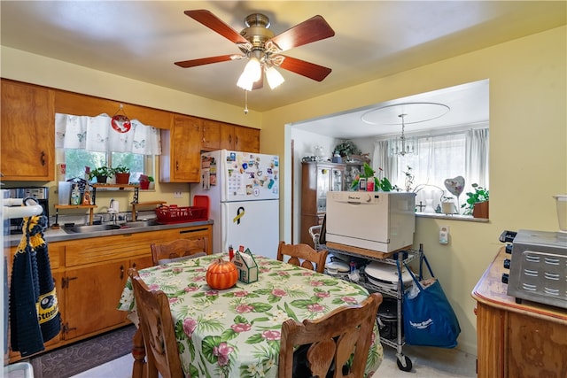 dining area featuring ceiling fan with notable chandelier and sink