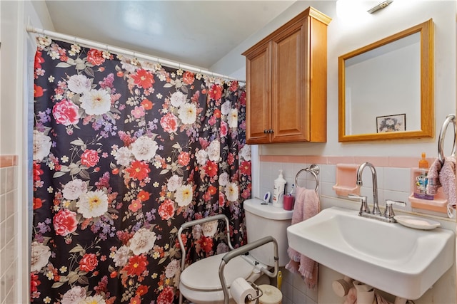 bathroom with tile walls, toilet, sink, and a shower with curtain