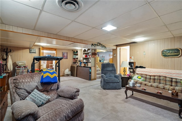 living room with wooden walls, carpet flooring, and a paneled ceiling