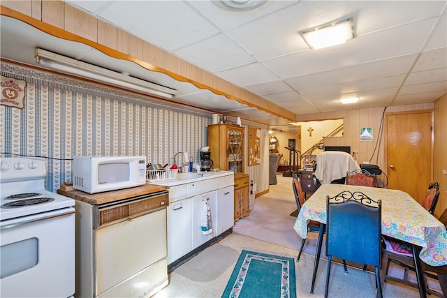 kitchen with a drop ceiling, white appliances, and light colored carpet