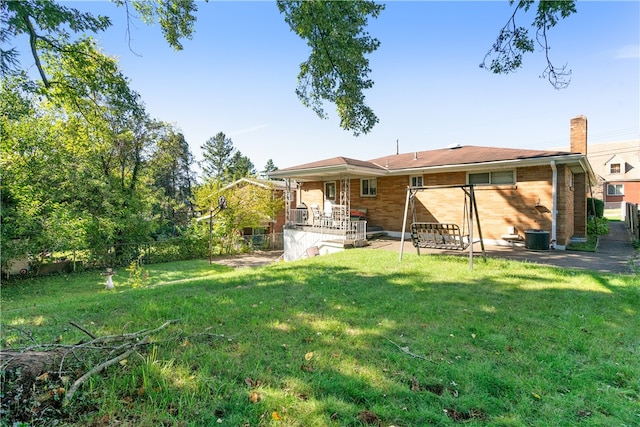 rear view of property with a patio, a yard, and central AC