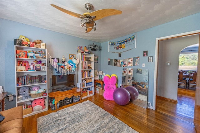 recreation room featuring a textured ceiling, wood-type flooring, and ceiling fan