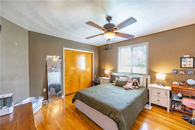 bedroom with light hardwood / wood-style floors, ceiling fan, and a closet