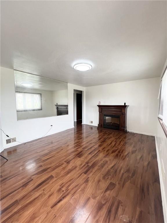 unfurnished living room featuring a glass covered fireplace, visible vents, and wood finished floors