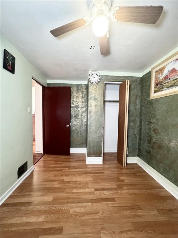 unfurnished bedroom with wood finished floors, ceiling fan, and baseboards