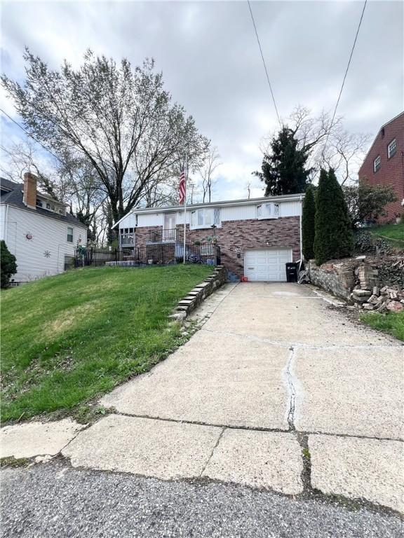view of front of home featuring an attached garage, driveway, and a front lawn