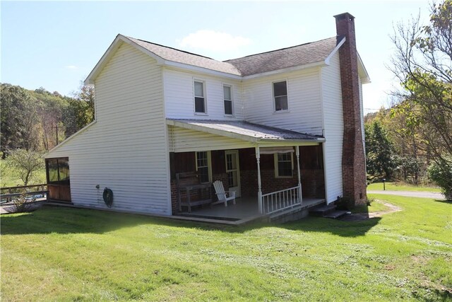 back of house featuring covered porch and a lawn