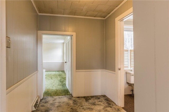 hall featuring crown molding, carpet, and wooden walls