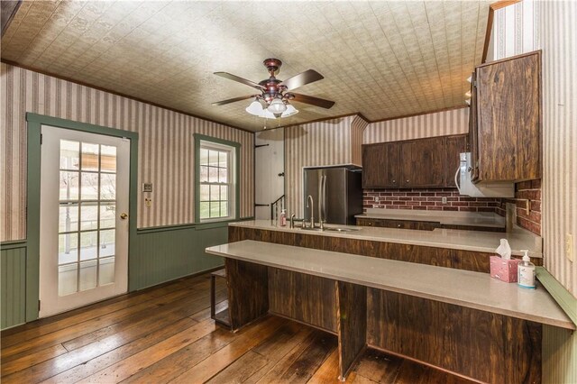 kitchen featuring a breakfast bar, sink, stainless steel fridge, kitchen peninsula, and dark wood-type flooring