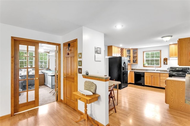 kitchen with black appliances, sink, and light hardwood / wood-style floors