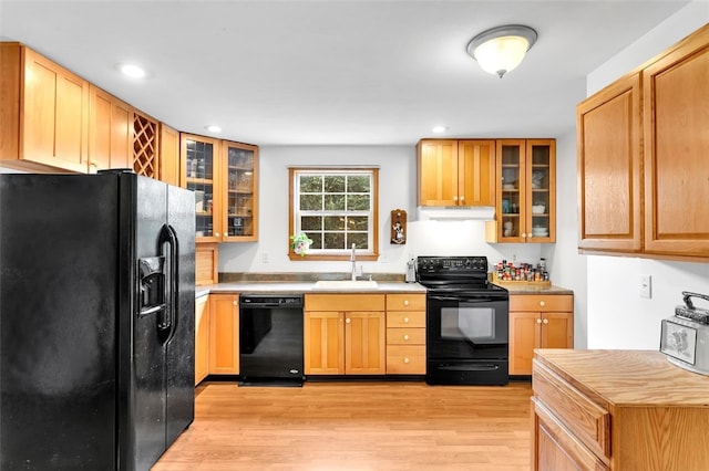 kitchen with light wood-type flooring, black appliances, and sink