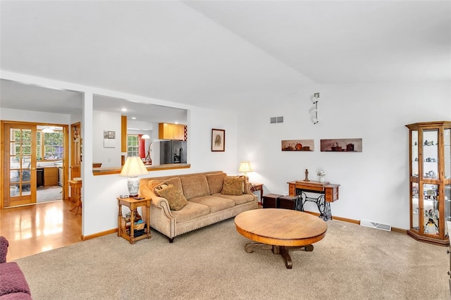 carpeted living room featuring vaulted ceiling and french doors