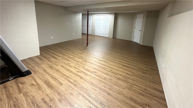 basement featuring light wood-type flooring and a paneled ceiling