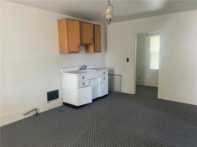 kitchen featuring dark colored carpet, hanging light fixtures, and sink