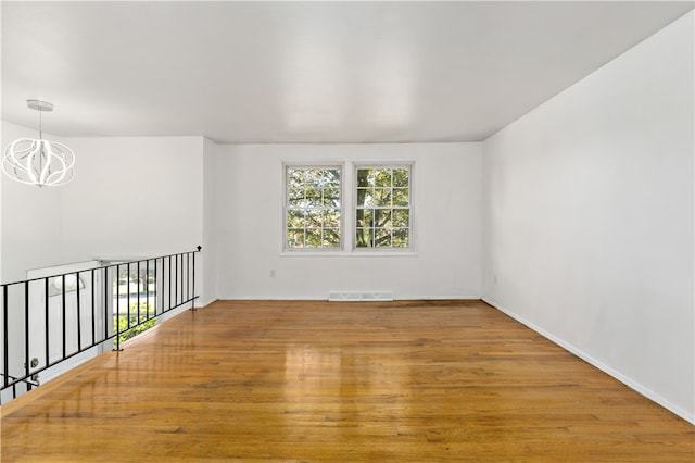 spare room with a notable chandelier and hardwood / wood-style floors