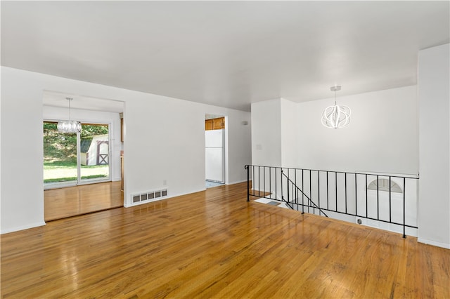 empty room featuring an inviting chandelier and hardwood / wood-style flooring