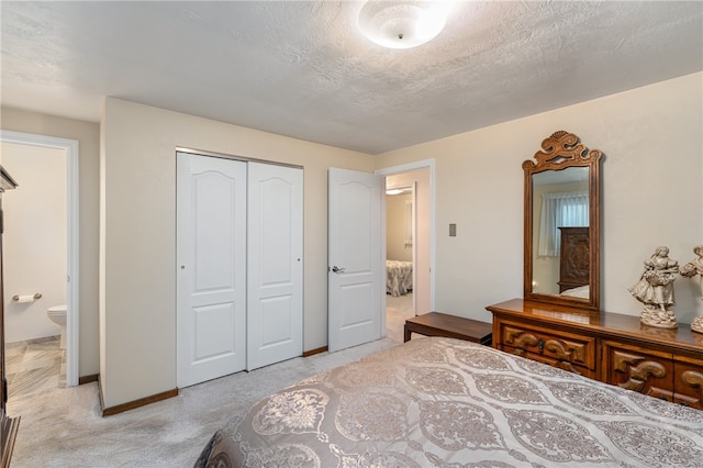 bedroom with a textured ceiling, connected bathroom, and a closet