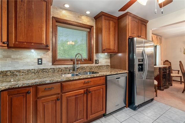 kitchen with light stone countertops, decorative backsplash, sink, and stainless steel appliances