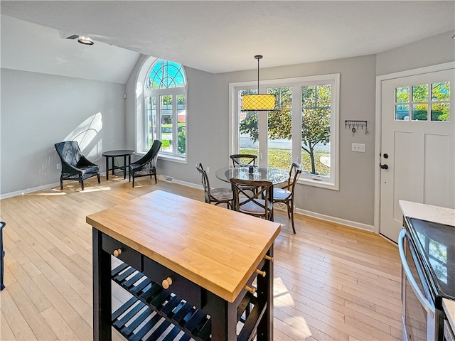 dining space featuring a healthy amount of sunlight, vaulted ceiling, and light hardwood / wood-style flooring