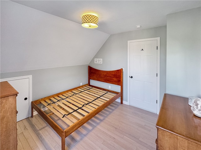 bedroom with vaulted ceiling and light hardwood / wood-style floors