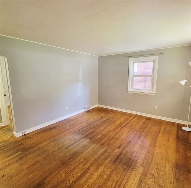 empty room featuring hardwood / wood-style flooring and crown molding