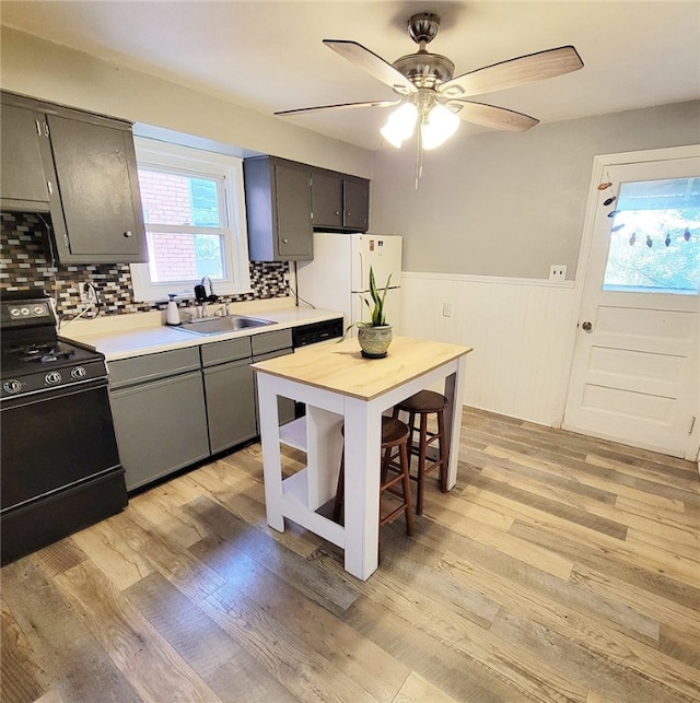 kitchen featuring light hardwood / wood-style floors, black range with electric stovetop, sink, white fridge, and backsplash